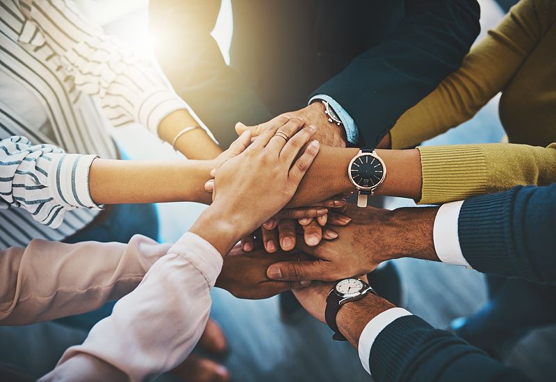 group of businesspeople joining their hands together in a huddle (1)